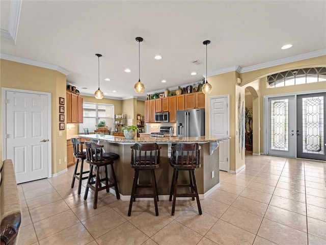 5461 White Ibis Dr, North Port, FL 34287 - kitchen featuring appliances with stainless steel finishes, crown molding, arched walkways, a spacious island, and light tile patterned floors