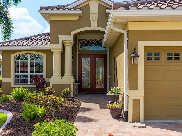 5461 White Ibis Dr, North Port, FL 34287 - view of exterior entry featuring french doors, a garage, a tiled roof, and stucco siding