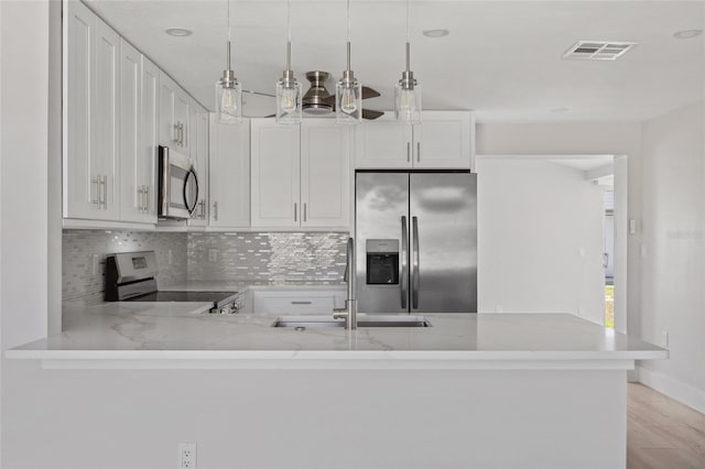 10517 Greenway Ave, Englewood, FL 34224 - kitchen featuring appliances with stainless steel finishes, a sink, backsplash, light stone countertops, and light wood-type flooring