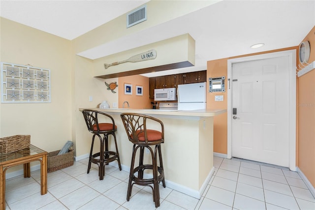 3160 Matecumbe Key Rd Unit 238, Punta Gorda, FL 33955 - kitchen with white appliances, light countertops, a kitchen bar, a peninsula, and baseboards