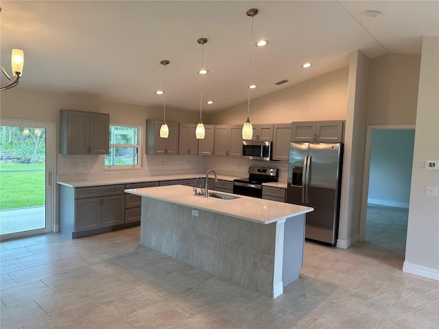 kitchen with stainless steel appliances, a sink, gray cabinetry, tasteful backsplash, and lofted ceiling