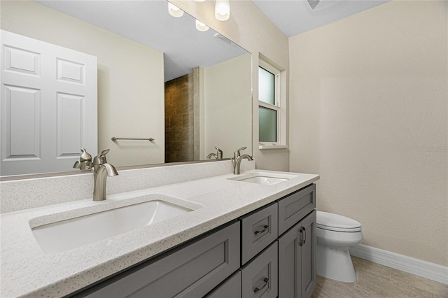 full bath featuring toilet, baseboards, and double vanity