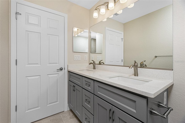 full bath featuring double vanity, a textured wall, and tile patterned floors