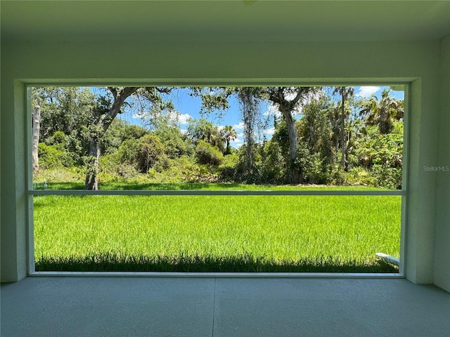 view of grassy yard with view of wooded area
