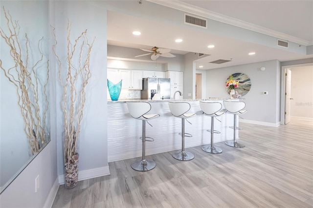 3329 Sunset Key Cir Unit 107, Punta Gorda, FL 33955 - kitchen featuring stainless steel refrigerator with ice dispenser, a kitchen breakfast bar, white cabinetry, baseboards, and light wood-type flooring