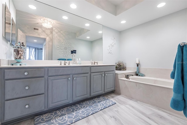 3329 Sunset Key Cir Unit 107, Punta Gorda, FL 33955 - bathroom featuring recessed lighting, double vanity, a garden tub, and wood finished floors