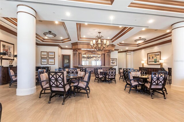 3329 Sunset Key Cir Unit 107, Punta Gorda, FL 33955 - dining area featuring decorative columns, crown molding, wood finished floors, a chandelier, and a tray ceiling