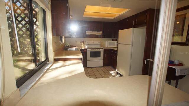 925 Fenton Ln Unit 11, Lakeland, FL 33809 - kitchen featuring white appliances, under cabinet range hood, light countertops, a sink, and a peninsula