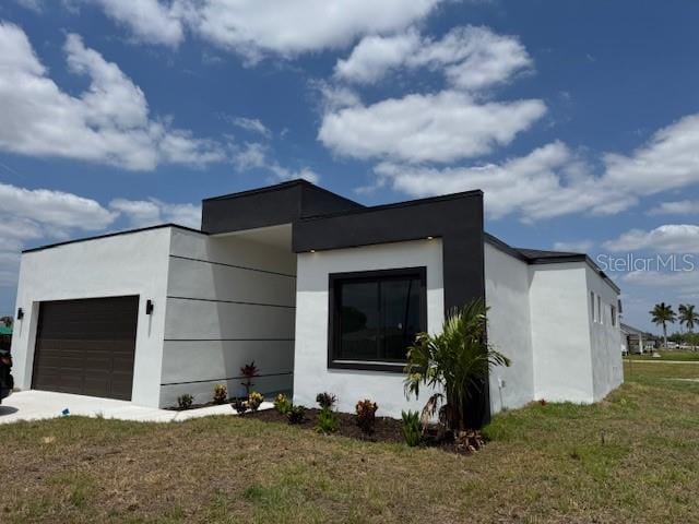 view of home's exterior with a garage, stucco siding, and a lawn