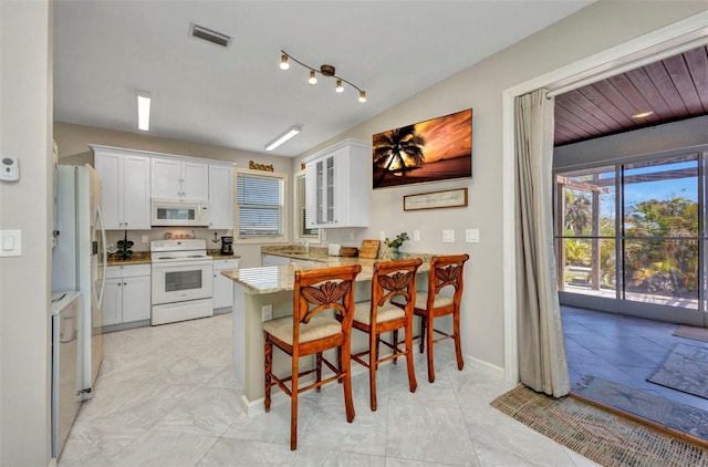 4231 Hollis Ave, Port Charlotte, FL 33953 - kitchen with white appliances, a peninsula, white cabinets, and glass insert cabinets