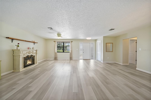 16615 Acapulco Rd, Punta Gorda, FL 33955 - unfurnished living room featuring a glass covered fireplace, a textured ceiling, a ceiling fan, light wood-style floors, and baseboards
