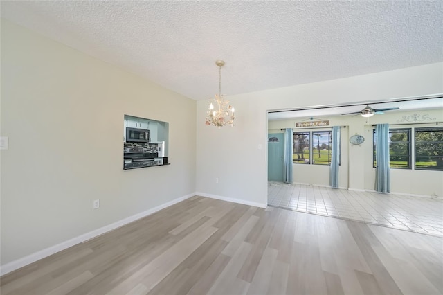 16615 Acapulco Rd, Punta Gorda, FL 33955 - empty room featuring a chandelier, a textured ceiling, a ceiling fan, wood finished floors, and baseboards
