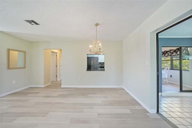 16615 Acapulco Rd, Punta Gorda, FL 33955 - unfurnished dining area with a chandelier, a textured ceiling, baseboards, and light wood-type flooring