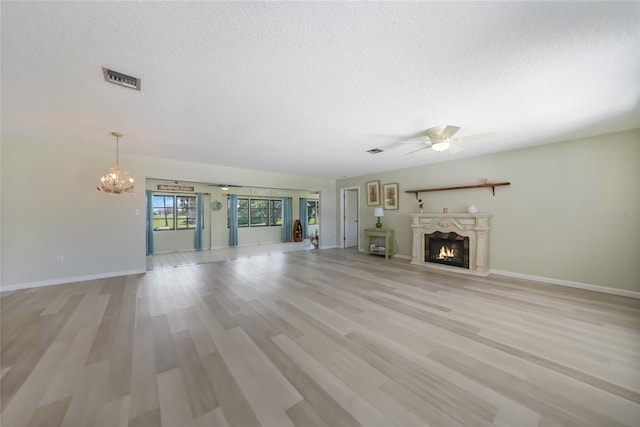 16615 Acapulco Rd, Punta Gorda, FL 33955 - unfurnished living room featuring a chandelier, ceiling fan, a textured ceiling, a warm lit fireplace, and baseboards