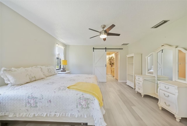 16615 Acapulco Rd, Punta Gorda, FL 33955 - bedroom with a barn door, light wood-style floors, and a ceiling fan