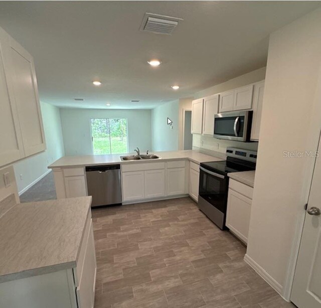 26 Postwood Dr, Palm Coast, FL 32164 - kitchen with stainless steel appliances, a peninsula, white cabinets, a sink, and recessed lighting