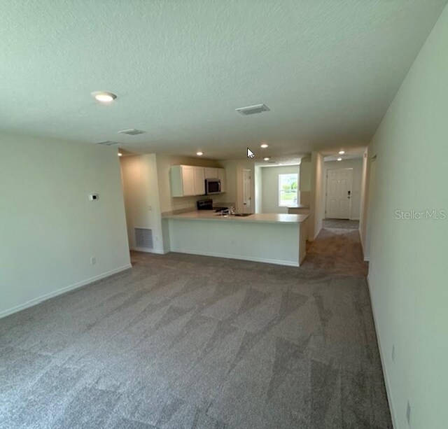 26 Postwood Dr, Palm Coast, FL 32164 - unfurnished living room featuring a textured ceiling, recessed lighting, light carpet, and baseboards