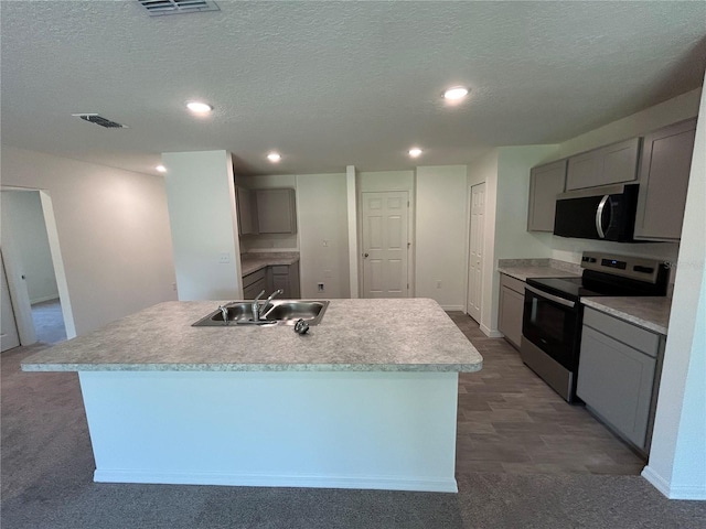 kitchen featuring stainless steel appliances, gray cabinetry, a center island with sink, a textured ceiling, and a sink