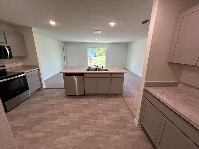 kitchen featuring appliances with stainless steel finishes, a sink, gray cabinetry, recessed lighting, and light countertops