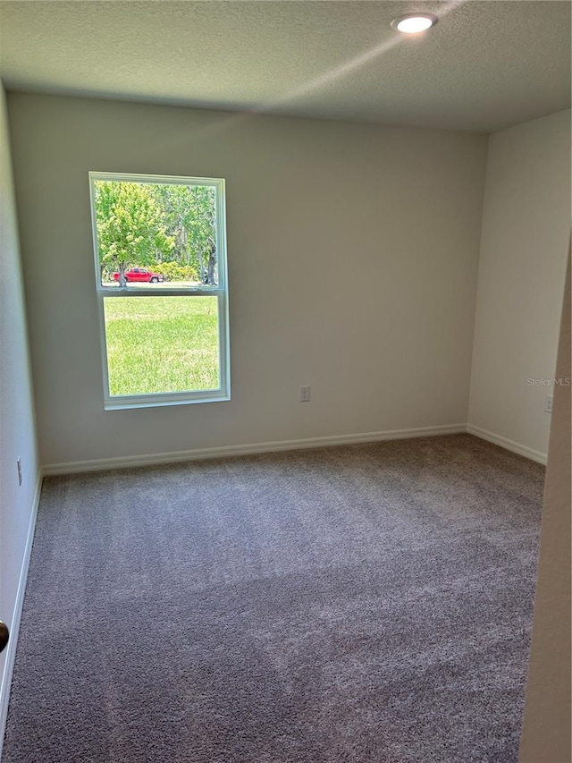 carpeted spare room with a textured ceiling and baseboards