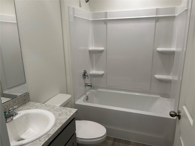full bath featuring toilet, vanity,  shower combination, and a textured wall