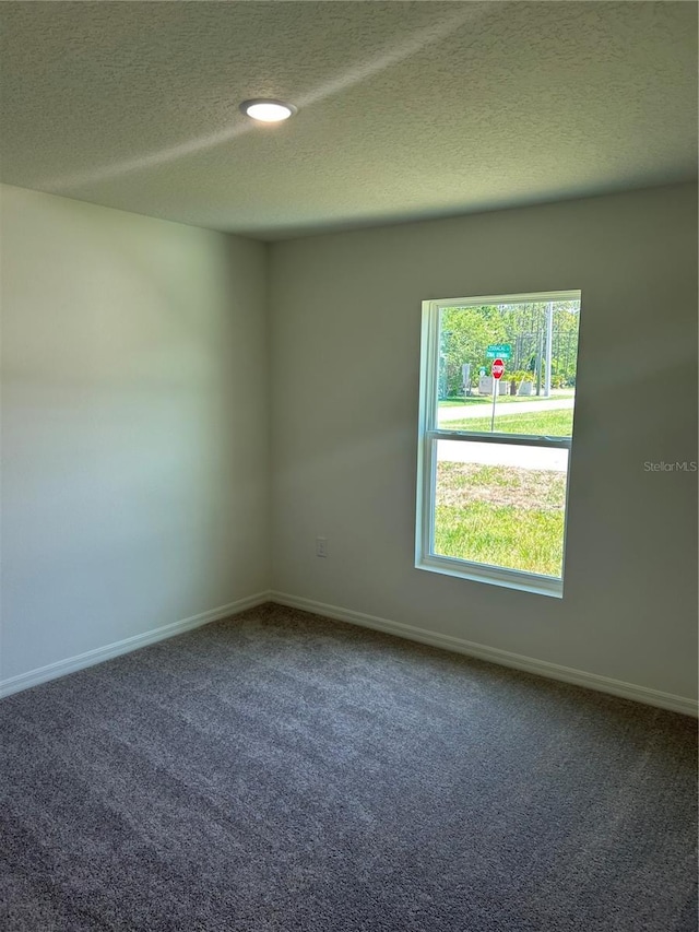 carpeted empty room featuring a textured ceiling and baseboards