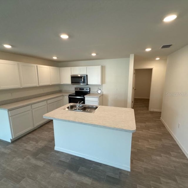 kitchen with appliances with stainless steel finishes, a sink, white cabinets, light countertops, and recessed lighting