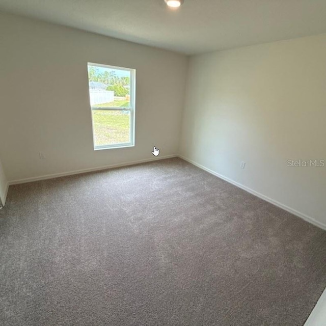 carpeted spare room featuring baseboards