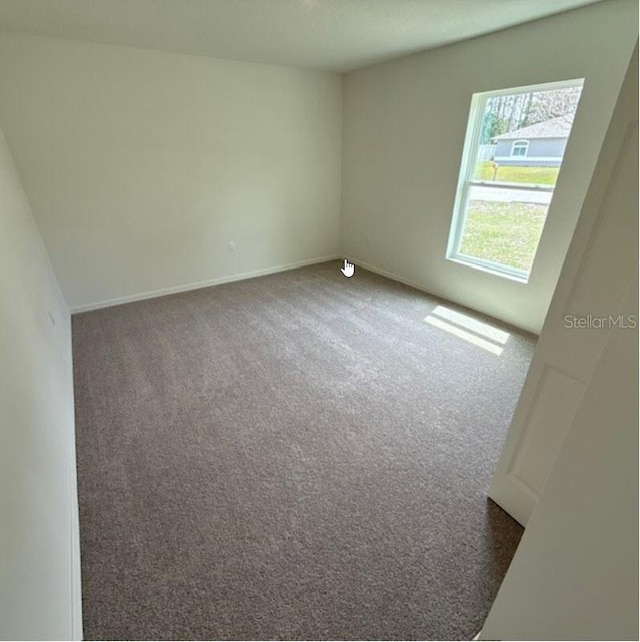 empty room featuring carpet floors and baseboards