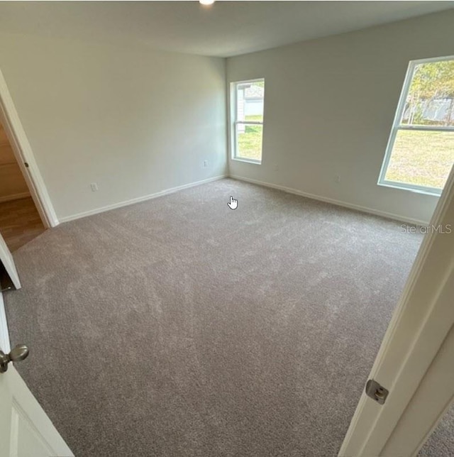 empty room featuring carpet floors and baseboards