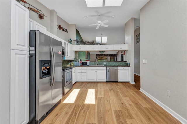 5046 San Rocco Ct, Punta Gorda, FL 33950 - kitchen featuring stainless steel appliances, a skylight, white cabinetry, baseboards, and light wood-type flooring