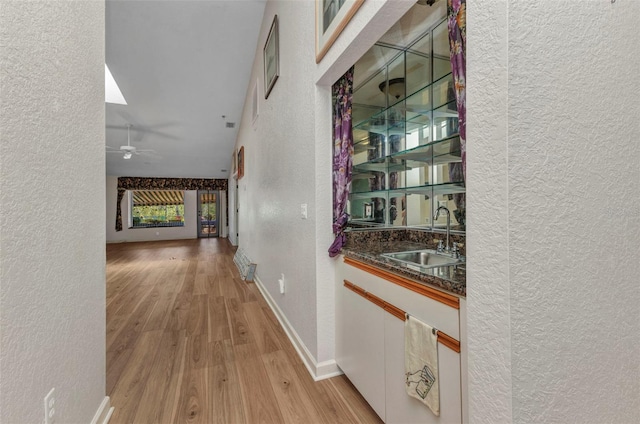 5046 San Rocco Ct, Punta Gorda, FL 33950 - corridor featuring a textured wall, a sink, light wood-style flooring, and baseboards