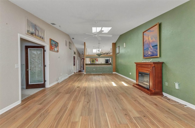 5046 San Rocco Ct, Punta Gorda, FL 33950 - unfurnished living room featuring a glass covered fireplace, light wood-type flooring, a ceiling fan, a skylight, and baseboards