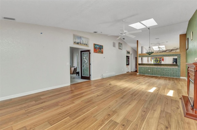 5046 San Rocco Ct, Punta Gorda, FL 33950 - unfurnished living room featuring light wood-style floors, vaulted ceiling, a skylight, ceiling fan, and baseboards