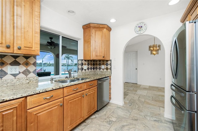 211 E Tarpon Blvd NW, Port Charlotte, FL 33952 - kitchen with stainless steel appliances, stone tile flooring, a sink, light stone counters, and arched walkways