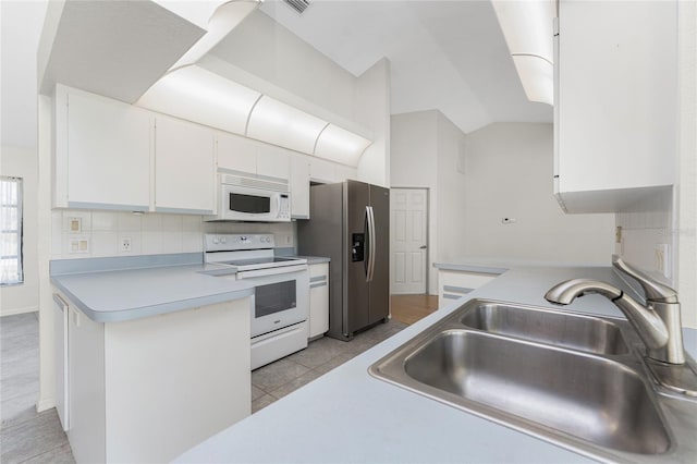 18111 Lake Worth Blvd, Port Charlotte, FL 33948 - kitchen featuring white appliances, a sink, white cabinetry, light countertops, and vaulted ceiling