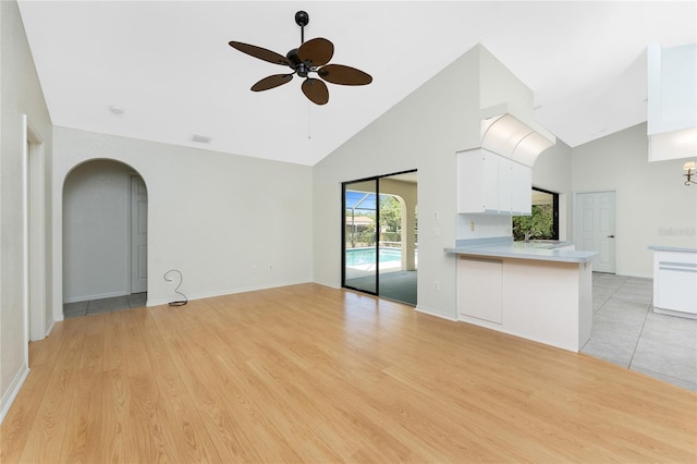 18111 Lake Worth Blvd, Port Charlotte, FL 33948 - unfurnished living room featuring high vaulted ceiling, ceiling fan, arched walkways, light wood finished floors, and a sink