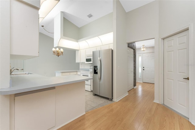 18111 Lake Worth Blvd, Port Charlotte, FL 33948 - kitchen with white appliances, a sink, a peninsula, high vaulted ceiling, and white cabinetry