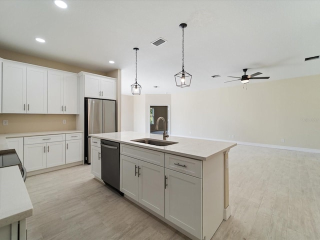 kitchen with a sink, dishwashing machine, light wood finished floors, light countertops, and recessed lighting