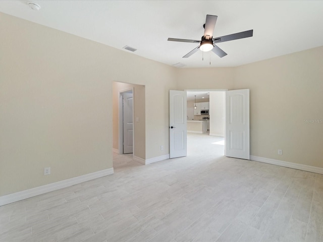 spare room with ceiling fan, baseboards, and light wood-type flooring