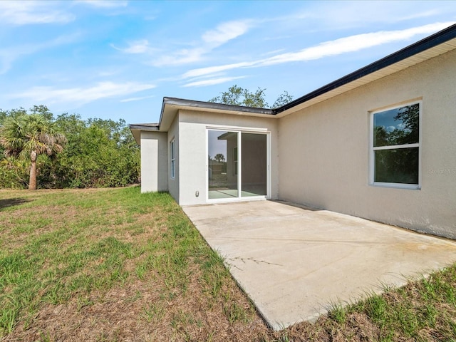 back of property with stucco siding, a patio area, and a yard