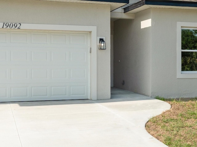 doorway to property with stucco siding, concrete driveway, and a garage