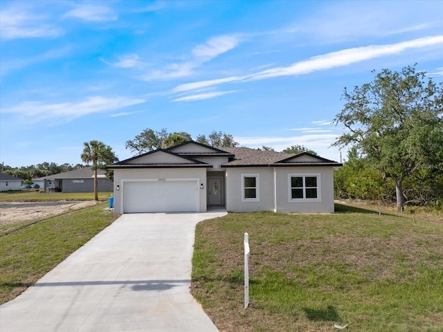ranch-style home featuring an attached garage, driveway, a front yard, and stucco siding