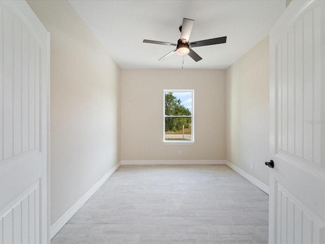 spare room with a ceiling fan, light wood-style flooring, and baseboards