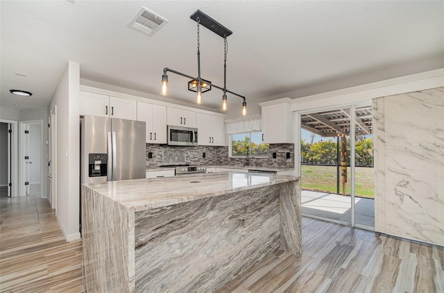 4282 Pocatella Ave, North Port, FL 34287 - kitchen featuring appliances with stainless steel finishes, a center island, decorative backsplash, light stone counters, and white cabinetry