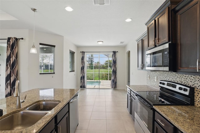 7505 Carissa, Punta Gorda, FL 33955 - kitchen featuring appliances with stainless steel finishes, a sink, dark brown cabinets, arched walkways, and tasteful backsplash