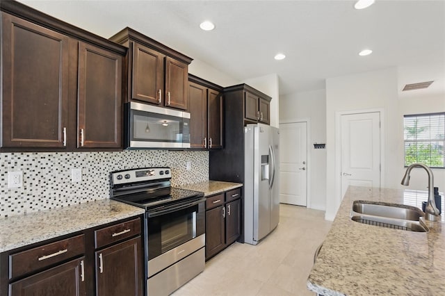 7505 Carissa, Punta Gorda, FL 33955 - kitchen with stainless steel appliances, a sink, backsplash, dark brown cabinetry, and light tile patterned floors