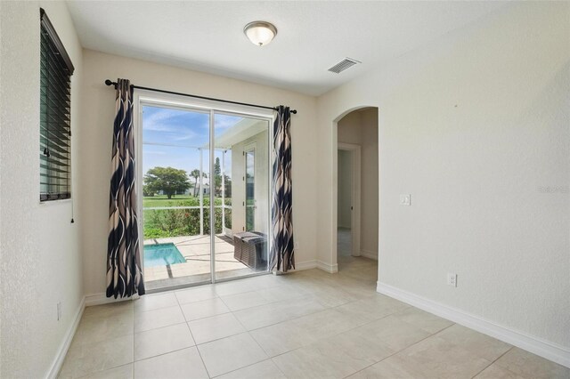 7505 Carissa, Punta Gorda, FL 33955 - empty room with arched walkways, baseboards, and light tile patterned flooring