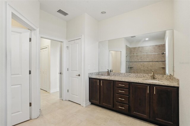 7505 Carissa, Punta Gorda, FL 33955 - bathroom featuring a tile shower, double vanity, tile patterned floors, and recessed lighting