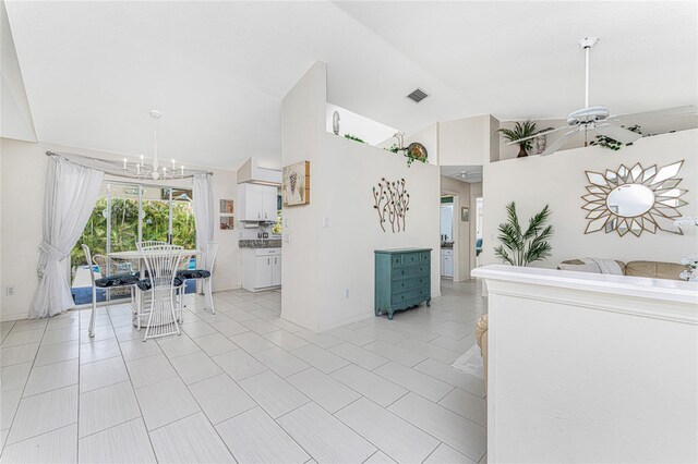 279 Mariner Ln, Rotonda West, FL 33947 - kitchen with a chandelier, vaulted ceiling, white cabinetry, light tile patterned floors, and baseboards